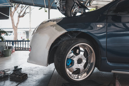 Denter or car mechanic serviceman check and fix body work and fiber bumper body part for fix and repair problem at car garage or repair shopの写真素材