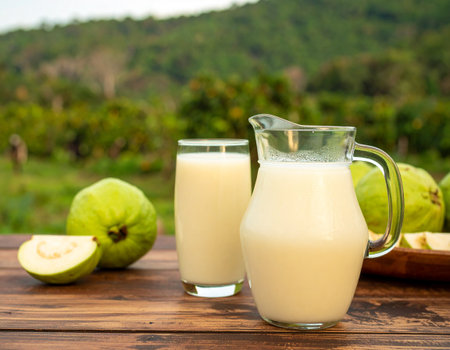 AI generated Chilled guava juice in glass pitcher with fresh guavas and slices on rustic table Tropical guava orchard background with farmers harvesting Perfect vitamin C drinks healthy refreshmentsの素材