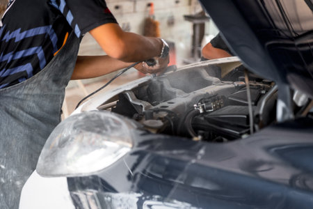 Denter or car mechanic serviceman check and fix body work and fiber bumper body part for fix and repair problem at car garage or repair shopの写真素材