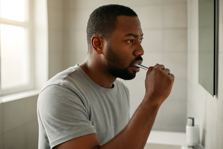 AI generated Black man in his 30s brushing his teeth in a modern bathroom with soft morning light. A calm, clean start to the day captured in a serene and intimate setting.の素材