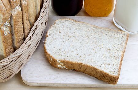 cut bread on cutting wooden board with milk and jam 