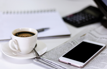 cup of coffee with Newspaper and smartphone on white table.の写真素材