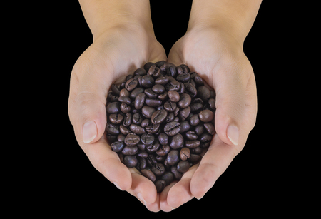 Coffee beans in male hands on black background.の写真素材