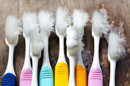 Old toothbrushes on wood table, concept toothbrush wear and tear.の写真素材