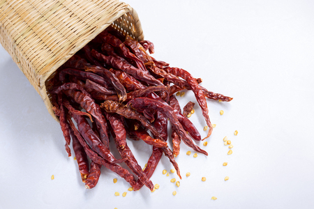 Closeup of red dry chili peppers in basket on white background.の写真素材