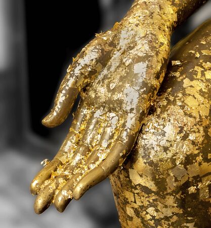 Gold leaf stick on Fingers of Buddha statue.の写真素材