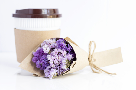 coffee cup with violet statice flower bouquet on white table. with copy space for text.の写真素材