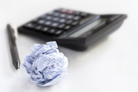 Crumpled paper ball with calculator on white table with copy space for text.の写真素材