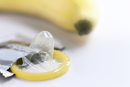 Condom with a yellow banana on white background with copy space for text.の写真素材