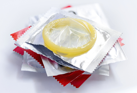 Stack condoms and one open pack on white background.の写真素材