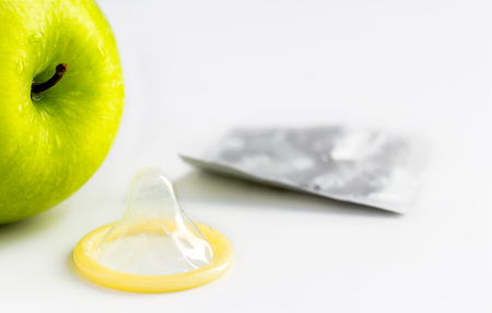 Green apple with an open condom on white background with copy space for text.の写真素材