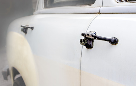 The old abandoned vintage car in the garage, door handle of the old car.