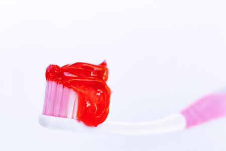 Red toothpaste is on the toothbrush isolated on white background. Dental Care Concept. with copy space for text. の写真素材