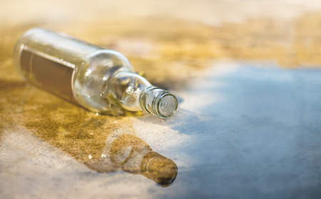 An empty bottle of wine is located on a wet cement floor.の写真素材