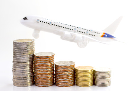 Coins stack with airplane on white background, concept of business growth, financial or money savings, with copy space for text.の写真素材