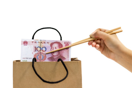The hand of female holds the chopsticks, which clamp the yuan banknote out of the paper bag.The concept of business growth, financial or money savings. with clipping path,の写真素材