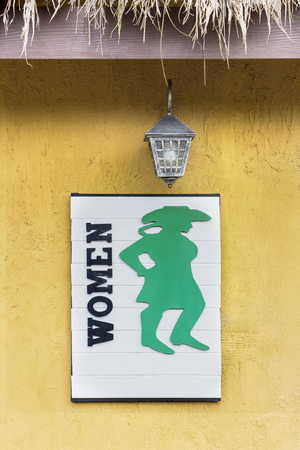 Toilet female signs on wood board with yellow rough cement wall background. Information board for toilets sign or restroom signs.の写真素材