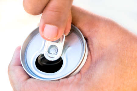 A hand opening a canned beverage with a man hand. Closeup of canned drink pull tab opening.の写真素材