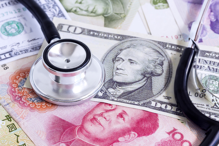 China yuan, us dollar banknote, and stethoscope on a pile of currencies banknotes. The concept of business growth, financial or money savings.の写真素材