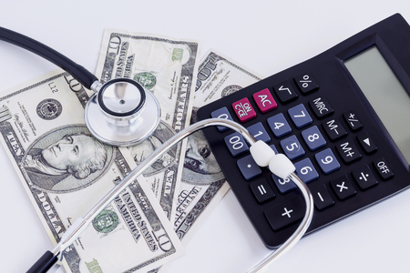 US dollar banknote, calculator, and stethoscope on a pile of currencies banknotes. The concept of business growth, financial or money savings.の写真素材