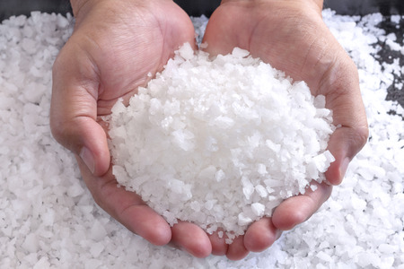 Sea salt in the hands of men. Sea salt is used for seasoning, preserving food and making beauty treatment the scrub with salt. selective focus.の写真素材