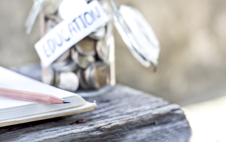 Open textbook, pencil, and coins in a glass bottle on the wooden table. The concept of intelligence comes from education. selective focus.の写真素材