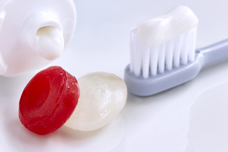 Toothbrush, toothpaste tube and candy on the white table. Candy causes tooth decay. Dental Care...