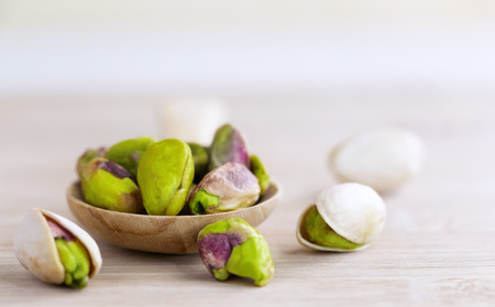 Pistachios in the wooden spoon on the wood table. Selective focus. with copy space for your text.
