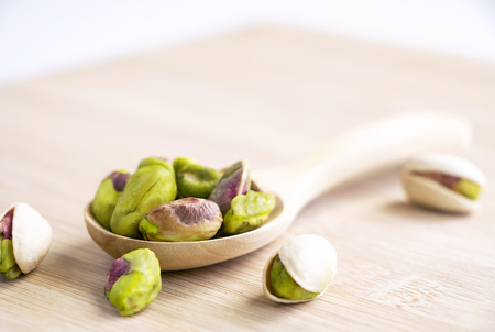 Pistachios in the wooden spoon on the wood table. Selective focus. with copy space for your text.の写真素材
