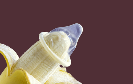 Condom and banana on the brown background. The concept of safe sex. with copy space for your text.の写真素材