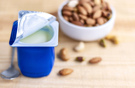 A breakfast of yogurt and a spoon placed on a wood table. Yogurt made from milk fermented by added bacteria, often sweetened and flavored.の写真素材