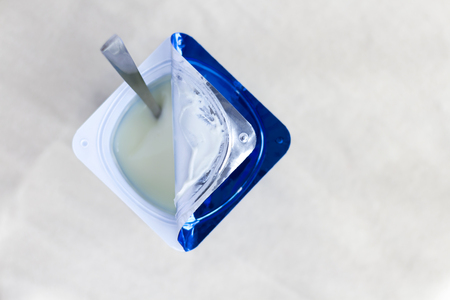 A breakfast of yogurt and a spoon placed on a cloth. Yogurt made from milk fermented by added bacteria, often sweetened and flavored.の写真素材