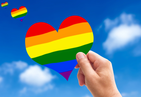LGBT heart. Man hands holding a heart-shaped bright Rainbow colors from the sky.の写真素材