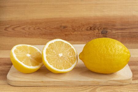 Fresh yellow lemon and half a lemon on a wooden table.