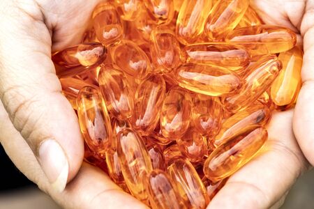 Woman holding fish oil capsules in hand. Fish oil capsules as a dietary supplement containing omega-3 and vitamin a is high for health care.の写真素材