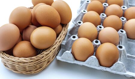 Fresh chicken eggs are placed in recyclable paper trays and basket in the kitchen.の写真素材
