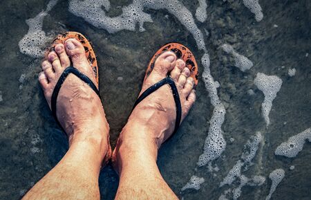 The man's legs were wearing slippers, standing in a dirty flood.の写真素材