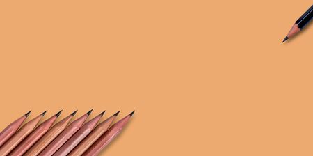 Brown pencils placed on a pale pinkish orange color (salmon) paper background with copy space for your image or text.の写真素材