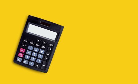Black calculator isolated on yellow background.の写真素材