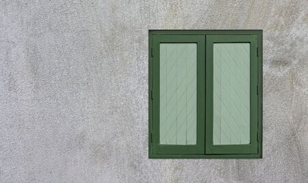 Green wooden windows are on the white cement wallの写真素材
