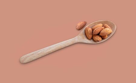 Almonds in spoon on brown background. Almonds are rich in nutrients, vitamins and minerals that are essential to the body.   の写真素材