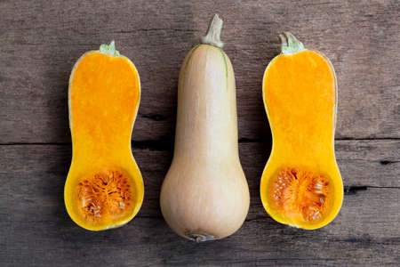 Butternut squash whole and sliced ââon a wooden table. Butternut is a bell-shape fruit with sweet orange-yellow flesh.の写真素材