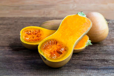 Butternut squash whole and sliced ââon a wooden table. Butternut is a bell-shape fruit with sweet orange-yellow flesh.の写真素材