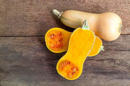 Butternut squash whole and sliced ââon a wooden table. Butternut is a bell-shape fruit with sweet orange-yellow flesh.の写真素材