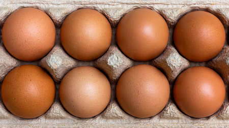 The eggs are packed in brown recycled paper boxes on a wooden table in the kitchen.の写真素材