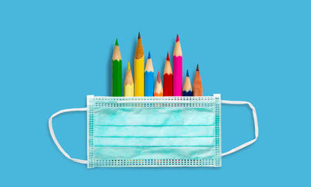 Green mask isolated on blue background with color pencils on blue background. Doctor mask fitting over the nose and mouth to protect against dust or virus.の写真素材