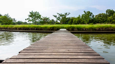 Old brown wooden bridge with trees and sky as background.の写真素材