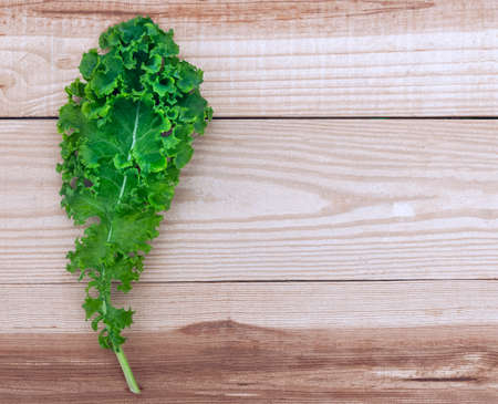 Fresh kale isolated on wooden table with copy space for your text or image.の写真素材