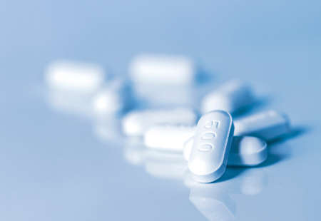 White medical pill on blue background.の写真素材