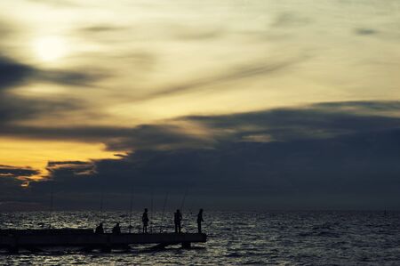 Fisherman local silhouette on thai sea with clouds orange skyの写真素材